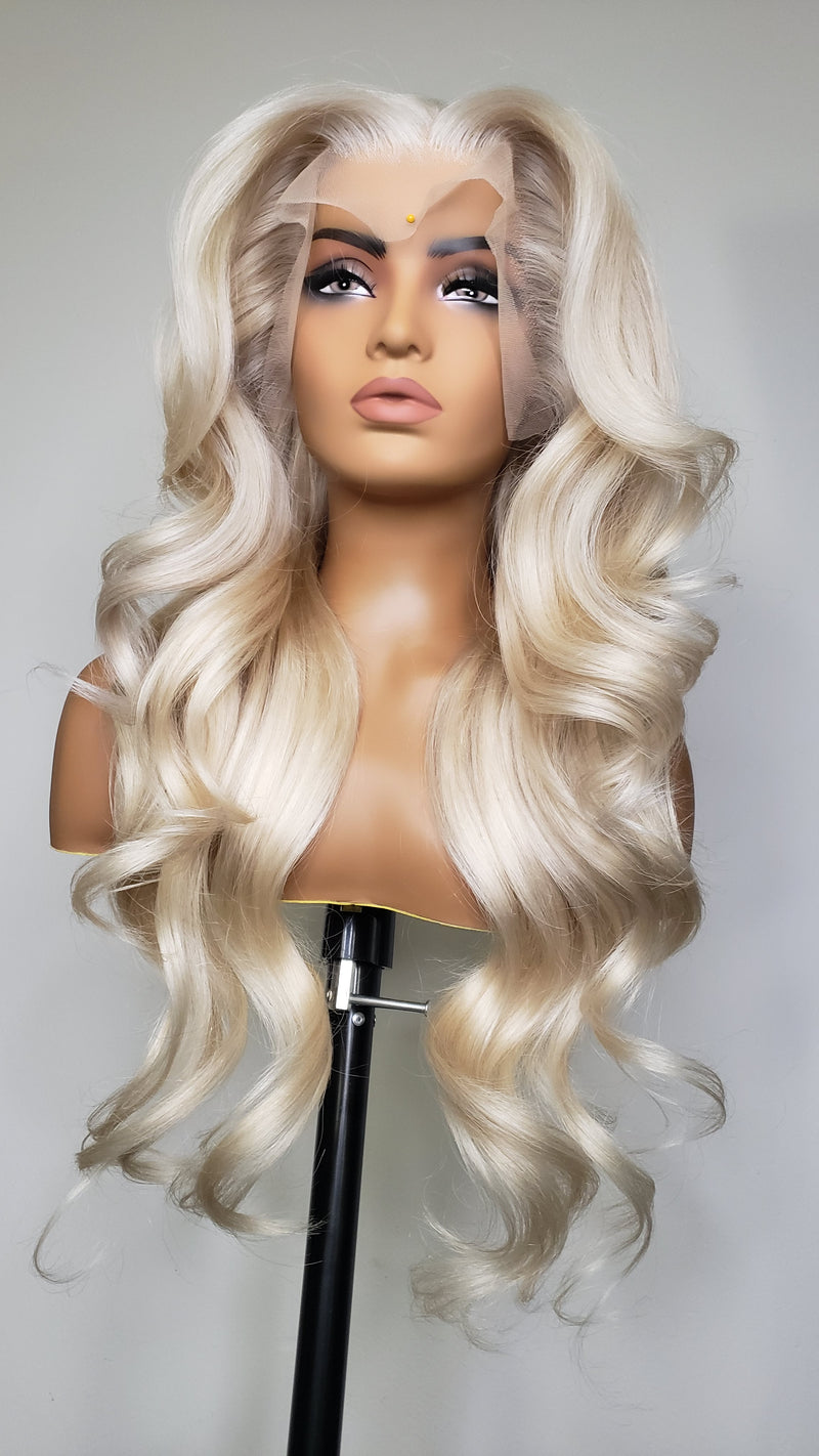 Long wavy platinum blonde wig with deep side-swept bangs displayed on a mannequin head against a light gray background.